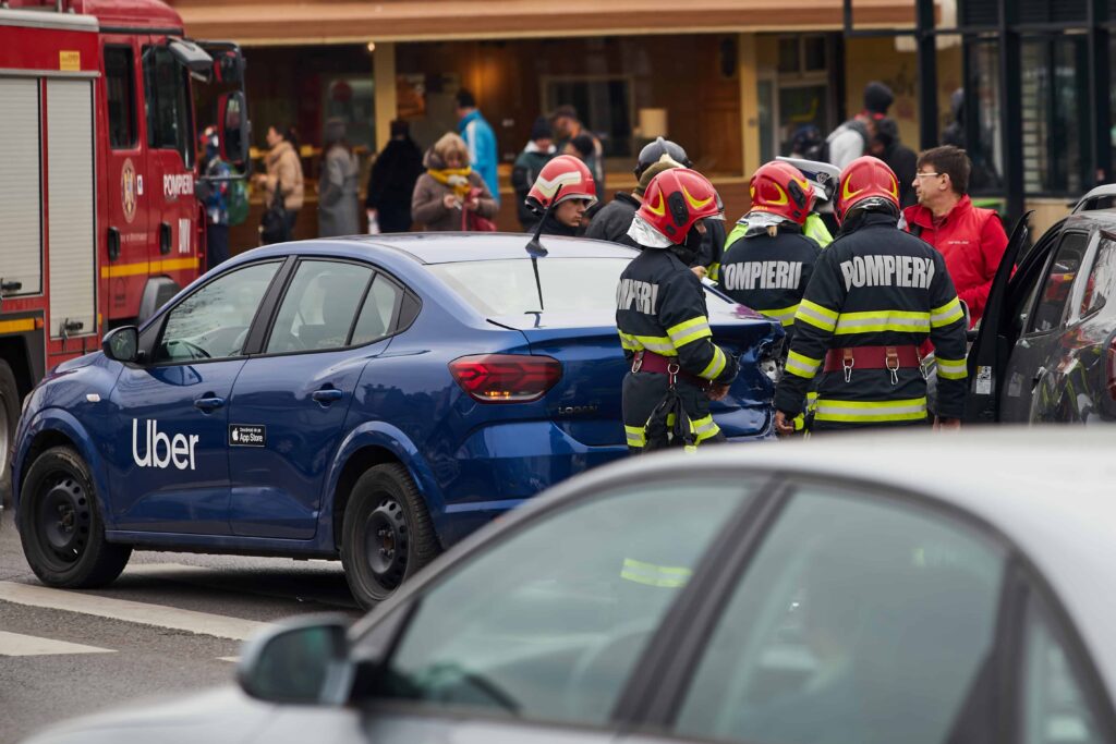 Firefighters and emergency responders assisting after Uber car accident on busy city street.