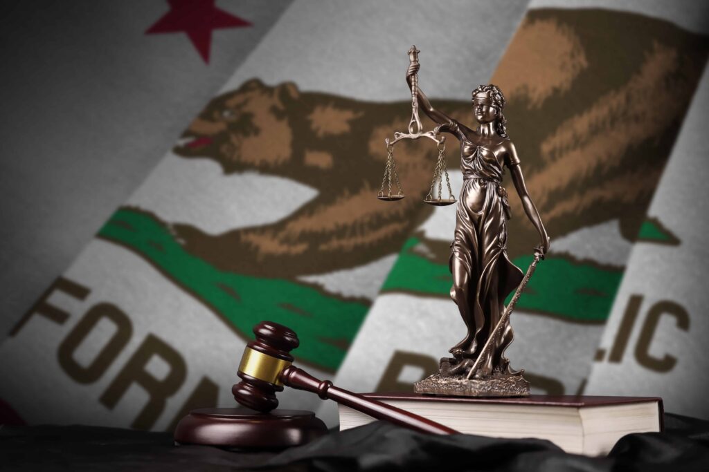 Lady Justice statue and judge&rsquo;s gavel in front of California state flag, symbolizing California personal injury and wrongful death law.