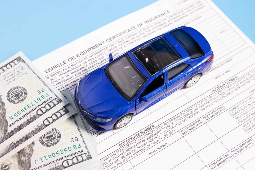 Auto insurance policy document with toy car and cash, representing vehicle coverage, premiums, and car insurance costs.