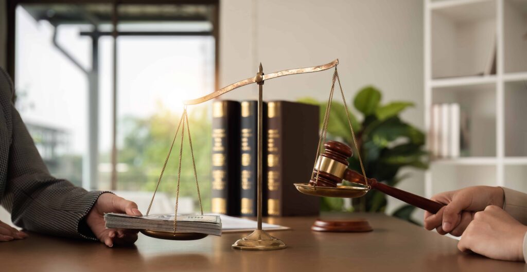 Scales of justice balancing stack of cash and judge&rsquo;s gavel, symbolizing financial compensation, legal settlement, and court verdict.