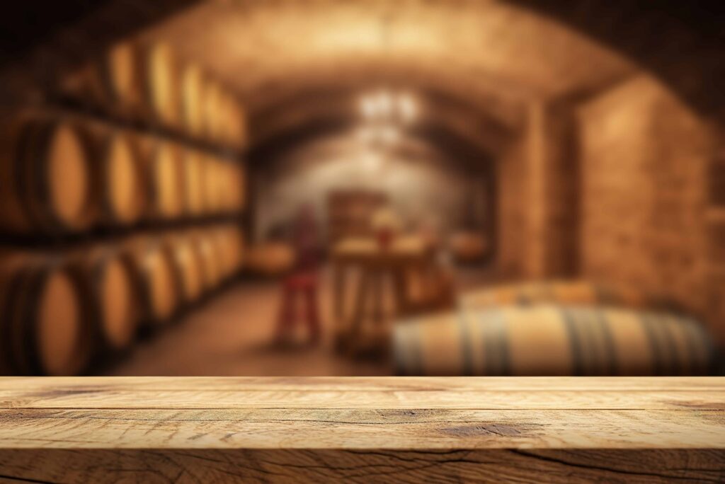 Empty wooden table in a wine cellar with oak barrels in the background, ideal for wine tasting or product display